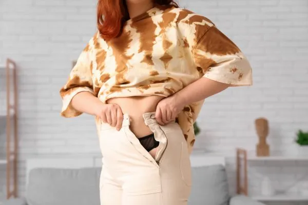 Image of woman trying to do her trousers up after pregnancy weight gain Halesowen