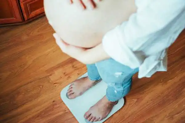 Image of woman weighing herself and experiencing weight gain through pregnancy Halesowen